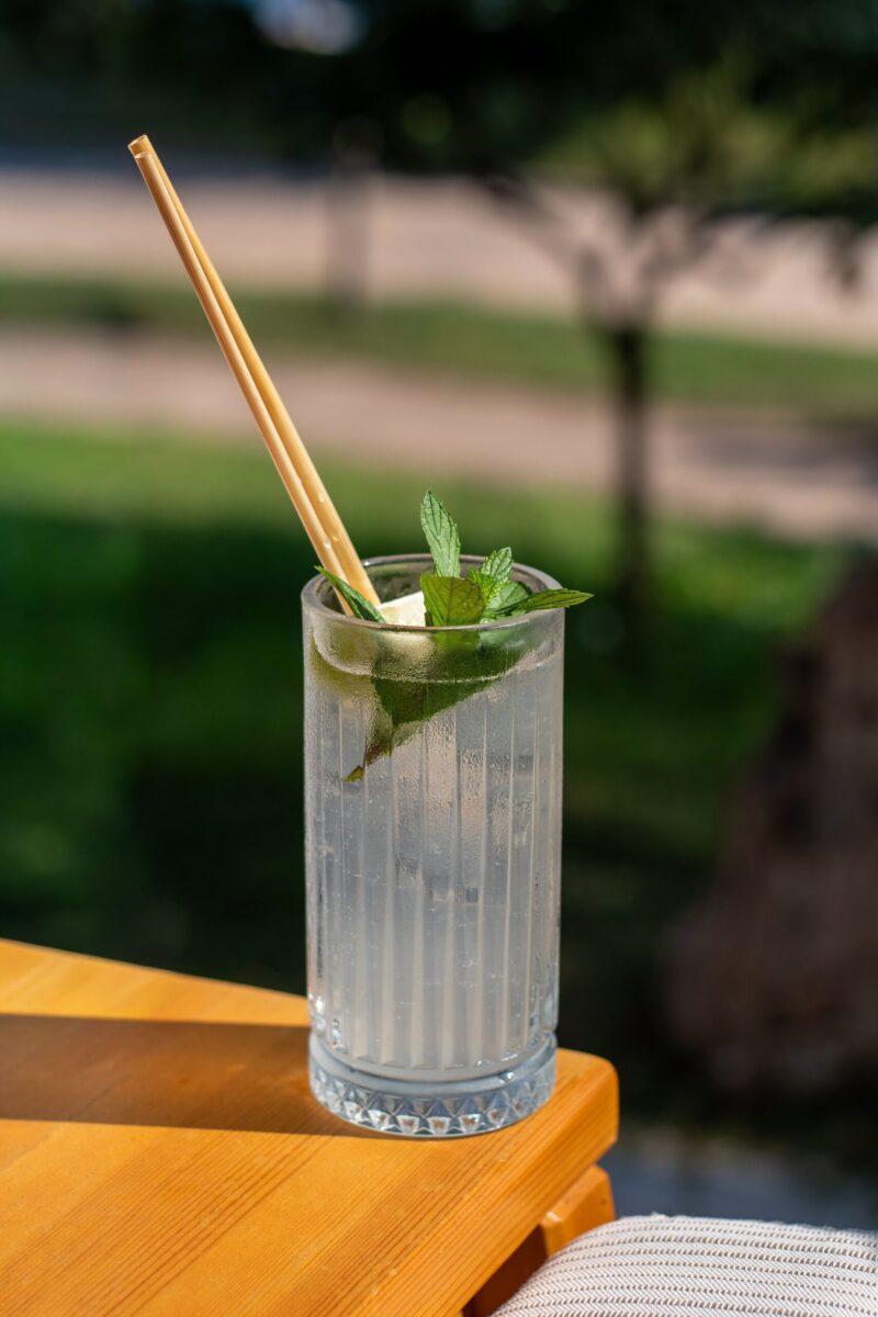 A chilled mojito cocktail with mint and lime, served in a tall glass on a sunny outdoor table.